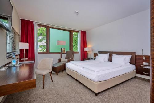 a bedroom with a large white bed and a desk at Asam Hotel in Straubing