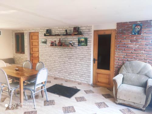 a dining room with a table and chairs and a brick wall at Guesthouse Mery in K'obulet'i