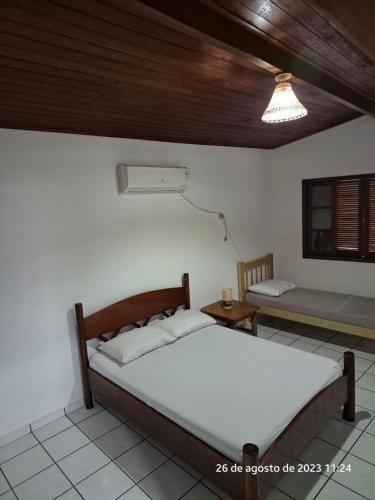 a bedroom with a bed and a table and a window at Casa em Ilhabela in Ilhabela