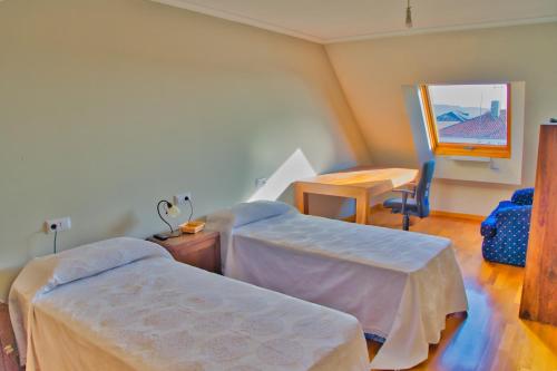Habitación con 2 camas, mesa y espejo. en Illas Atlánticas, en Ribeira