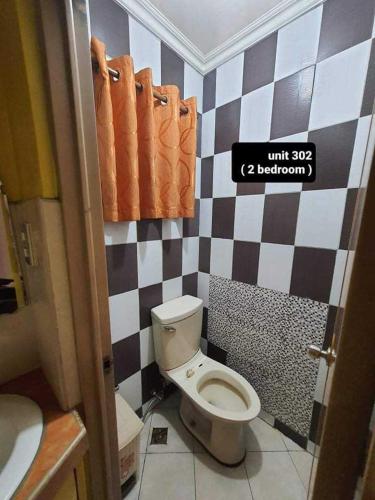 a bathroom with a toilet and a black and white checkered wall at ASHBURN'S TRANSIENT BAGUIO - 3rd to 5th floor BASIC SLEEP and GO Accommodation, WITH PARKING, NO ELEVATOR in Baguio