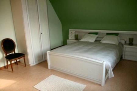 a bedroom with a white bed and a green wall at B&B Heerlijkhyd in Hertsberge