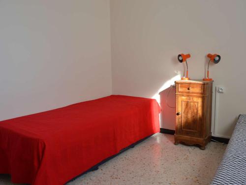 - une chambre avec un lit rouge et une commode en bois dans l'établissement Appartement T2 tout équipé, 4 couchages, proche plage et centre - Parking privé, Le Grau-du-Roi - FR-1-250-102, au Grau-du-Roi