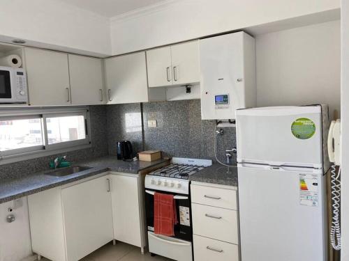 a kitchen with white cabinets and a white refrigerator at Departamento Hipólito Irigoyen in Santa Fe