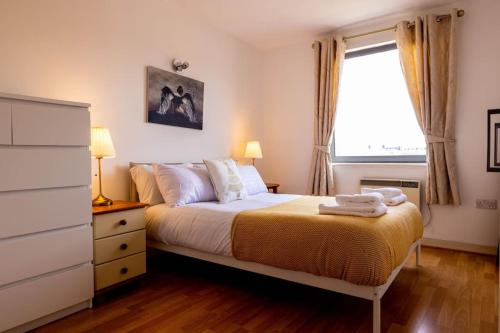 ein Schlafzimmer mit einem Bett mit einer Kommode und einem Fenster in der Unterkunft IGM 2beds Property in London