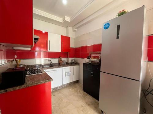 a red and white kitchen with a white refrigerator at apartment on the beach in El Harhoura