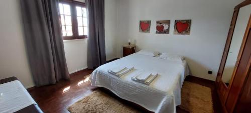 a bedroom with a white bed and a window at Vivenda Alju in Ourém