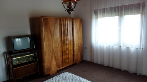 a room with a television and a wooden cabinet at Yanks Idila in Zlatibor