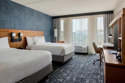 a hotel room with two beds and a desk at Courtyard by Marriott Philadelphia South at The Navy Yard in Philadelphia