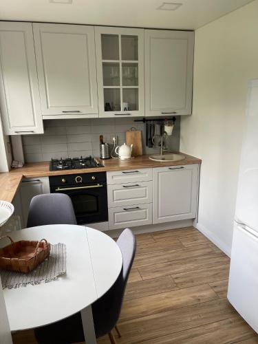 a kitchen with white cabinets and a table with chairs at Arena apartment in Panevėžys