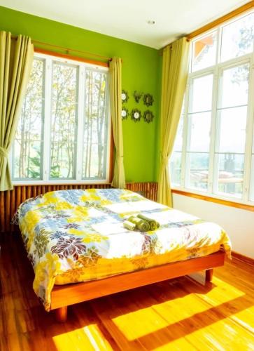 a bed in a room with green walls and windows at One khaokho homestay in Khao Kho