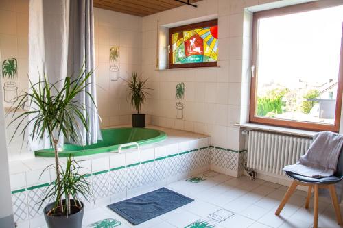 ein Bad mit einer Badewanne mit Pflanzen und einem Fenster in der Unterkunft Gemütliche Galerie-Wohnung in Biberach in Biberach an der Riß
