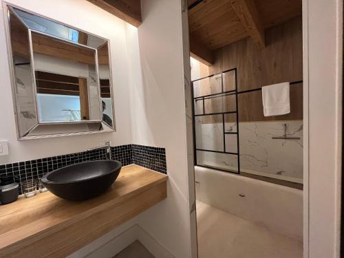 ein Badezimmer mit einem schwarzen Waschbecken und einem Spiegel in der Unterkunft LE CLOS DE FLO 17 in Saint-Rogatien