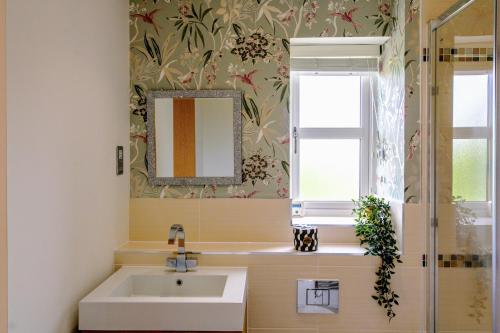 a bathroom with a sink and a mirror and a window at Sophisticated 5-Bedroom, 3 bathroom House with Free Private Parking in Milton Keynes by HP Accommodation in Milton Keynes