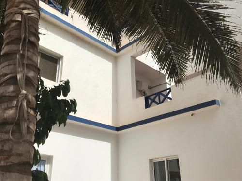 a white building with blue trim and a palm tree at Maio Relax in Vila do Maio