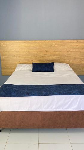 Cama con cabecero de madera y almohada azul en Hotel Luna Sanjuanera en San Juan del Cesar