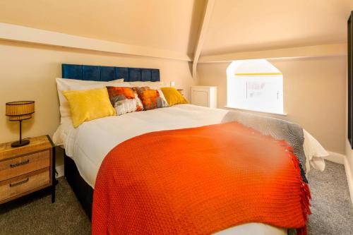 a bedroom with a large bed with an orange blanket at Clock Tower Retreat - Sea View Apartments in Morecambe in Morecambe