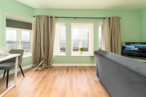 a living room with a couch and a table and windows at Clock Tower Retreat - Sea View Apartments in Morecambe in Morecambe