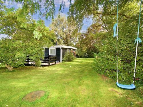 a yard with a campsite in the background with a tree at 4 person holiday home in Holb k in Holbæk