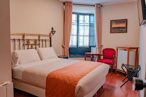 um quarto de hotel com uma cama e uma cadeira vermelha em Hostal Colonial Potosi em Potosí