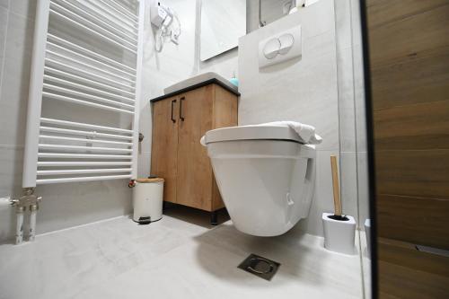 a white bathroom with a toilet and a wooden cabinet at Apartman Drvorez-direktno na ski stazi in Jahorina