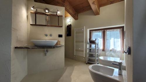 een badkamer met 2 wastafels, een toilet en een raam bij Widy's House in Bussoleno