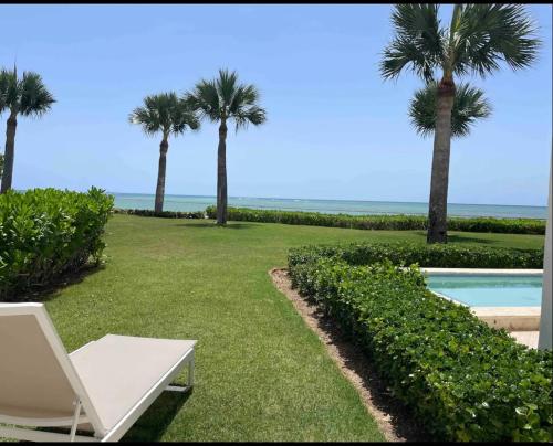 ein weißer Stuhl im Gras neben einem Pool in der Unterkunft En la playa con piscina in Punta Cana