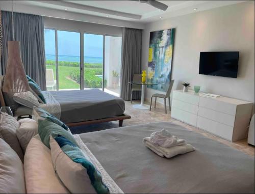 Dormitorio con sofá, cama y TV en En la playa con piscina en Punta Cana