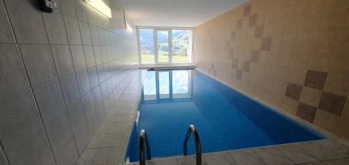 una grande piscina blu in un bagno con finestra di Stilvolle Wohnung mit traumhaftem Bergblick a Disentis