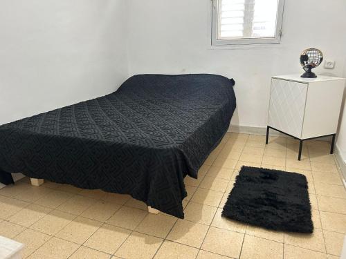 1 dormitorio con 1 cama con edredón negro en LUXURY privet room near Tel Aviv en Petaẖ Tiqwa