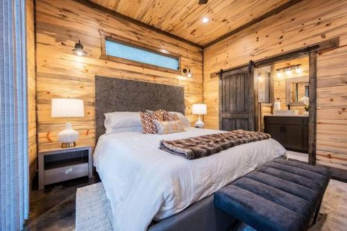 a bedroom with a large bed and a wooden wall at The Blaylock Cabin, 2 King, Hot Tub, Pet Friendly! in Broken Bow