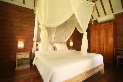 a bedroom with a white bed with a canopy at Mahamustika Riverside in Canggu