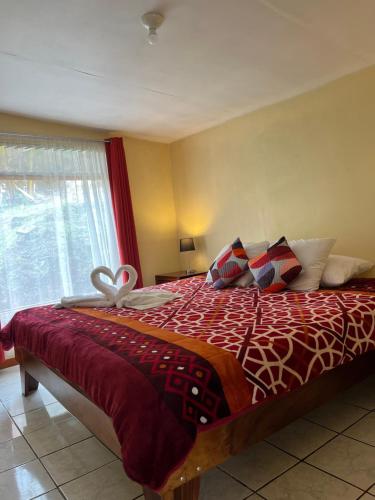 a bedroom with a bed with a red comforter and a window at La Casa Bonita in Monteverde Costa Rica