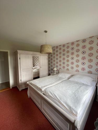 a bedroom with a large white bed with floral wallpaper at Haus-Seeschwalbe-Wohnung-3 in Nieblum
