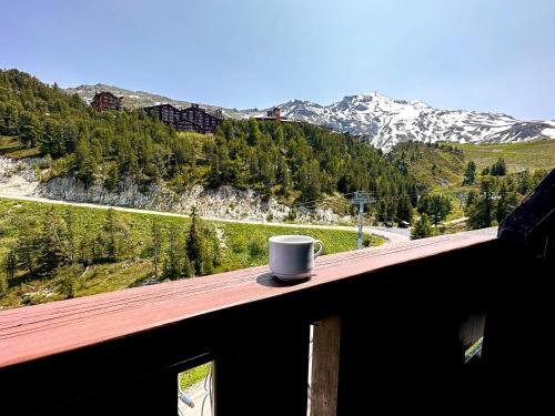 a coffee cup sitting on a wooden ledge with a mountain at Appartement style chalet 5* vue Mont-Blanc - Arc 1950 in Arc 1950