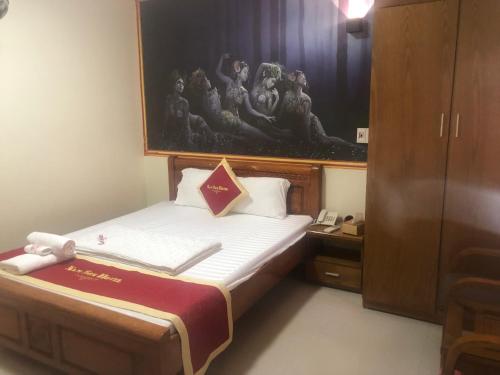 a small bedroom with a bed and a painting on the wall at Hotel Nam Sơn in Lương Kê