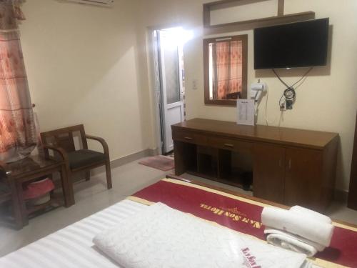 a hotel room with a bed and a tv and a room at Hotel Nam Sơn in Lương Kê