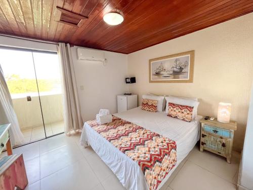 a bedroom with a bed and a large window at Pousada do Albatroz in Cabo Frio