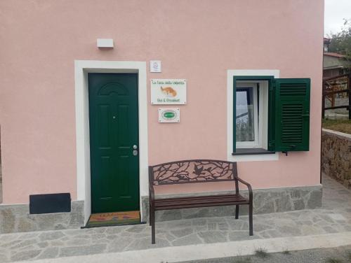 a bench sitting outside of a pink building with a green door at LA TANA DELLA VOLPETTA - Bed & Breakfast in Stella