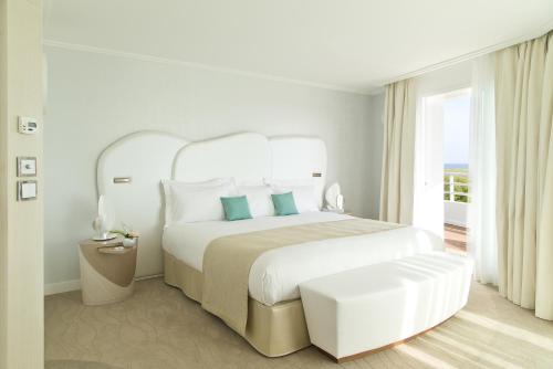 a white bedroom with a large bed and a window at Miramar La Cigale Hotel Thalasso & Spa in Arzon