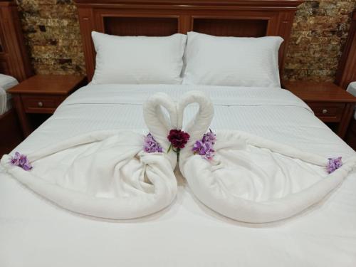 two white towels are folded into hearts on a bed at Durrat Nizwa Inn in Nizwa