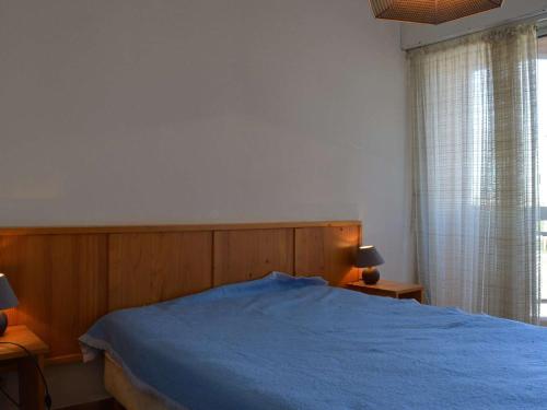 une chambre avec un lit bleu et une fenêtre dans l'établissement Appt charmant 2P avec terrasse, proche plage, parking, BBQ - Saint-Cyprien Plage - FR-1-225D-34, à Saint Cyprien Plage