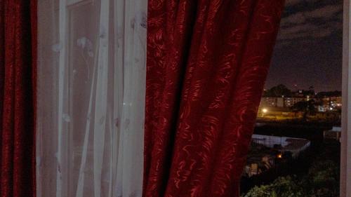 Una cortina roja en una ventana con la noche en Greenzone Luxury 1 Bed Apartment, en Nairobi