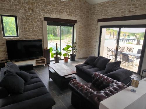 a living room with couches and a flat screen tv at Mas L'Escale des Dentelles in Aubignan