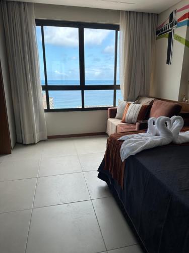 um quarto com uma cama e um sofá e uma janela grande em Salvador barra em Salvador