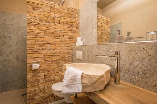 a bathroom with a toilet and a stone wall at Landhotel und Gasthof Hirsch Hüttenreute in Hoßkirch