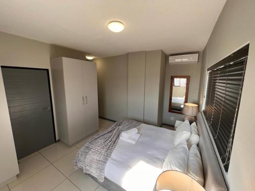 a bedroom with a white bed and a window at Le grand Hideout in Windhoek