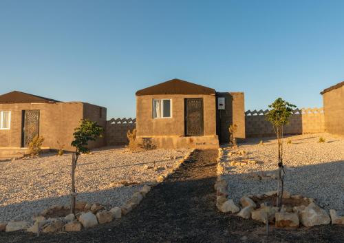 two trees in front of a building in the desert at Dana Sunset Eco Camp in Dana
