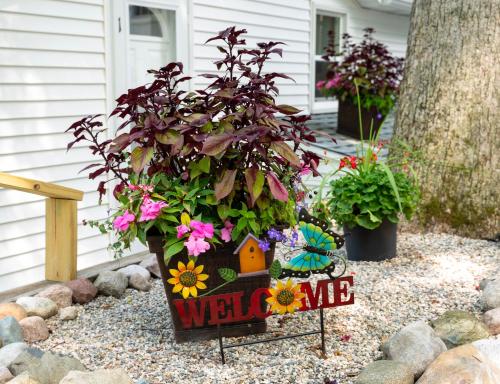 un cartel de bienvenida con una planta en un jardín en Knotty Pine Haven C1 en Greenville