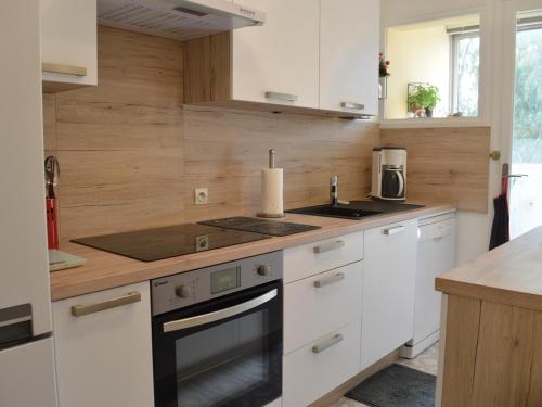 une cuisine avec des armoires blanches et un four à plaques de cuisson dans l'établissement Appartement 3 pièces climatisé avec garage, proche plage à Fréjus - FR-1-226A-72, à Fréjus